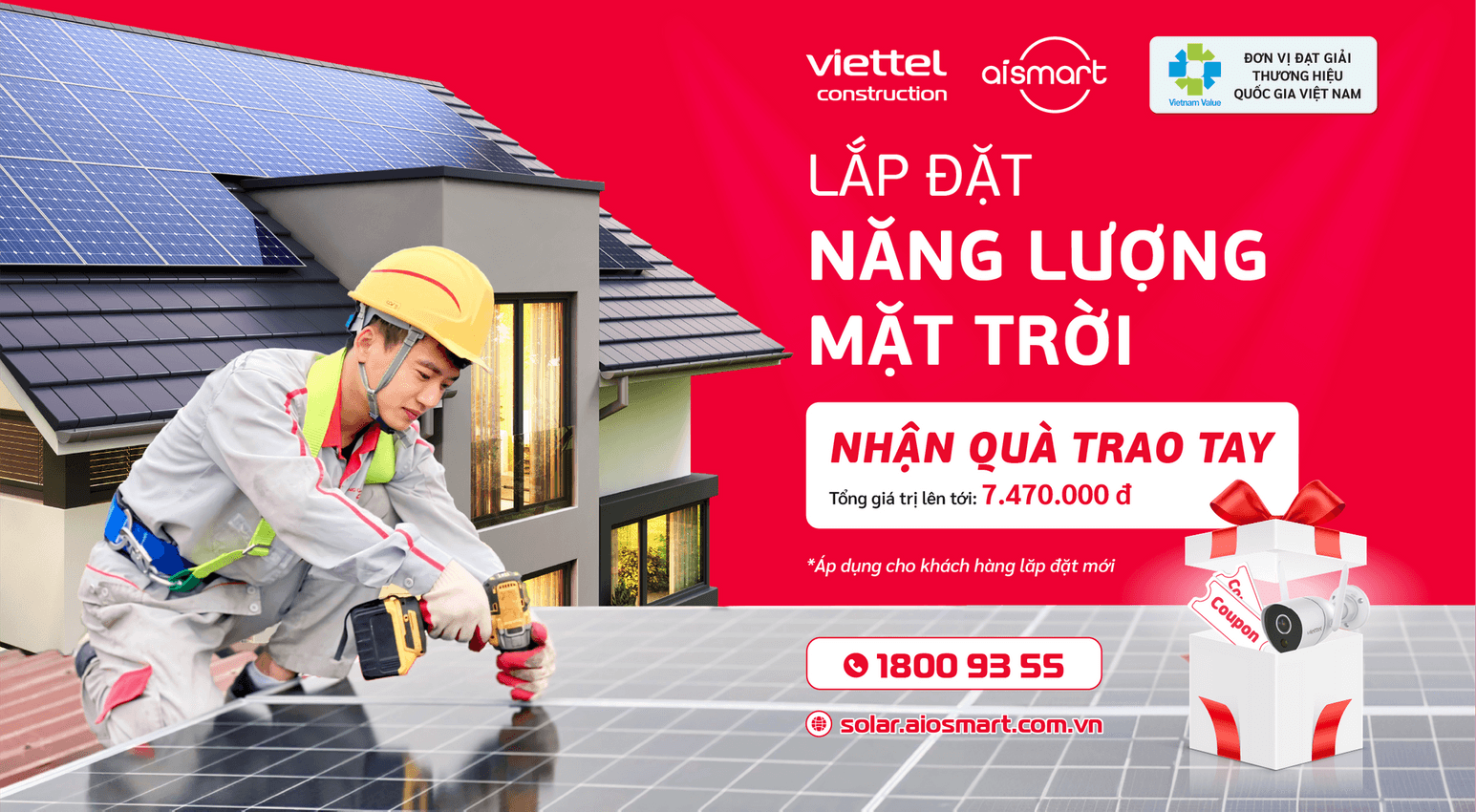 Worker in safety helmet installing solar panel on roof with solar panels and house background